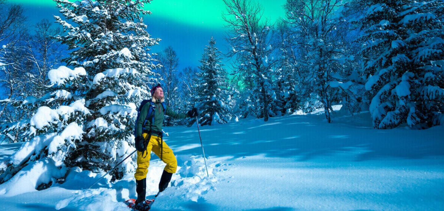 Lady enjoying the northern lights with snowshoes