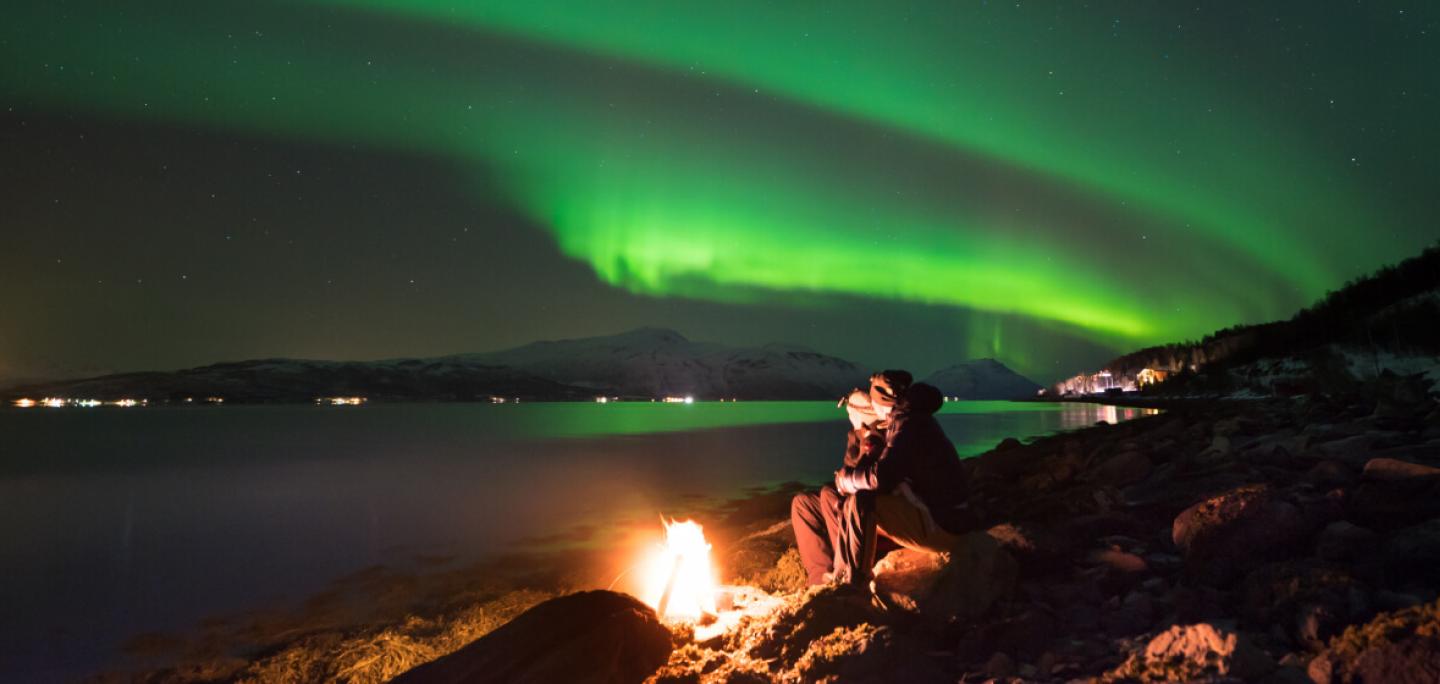 Enjoying the northern lights around a bonfire at the beach