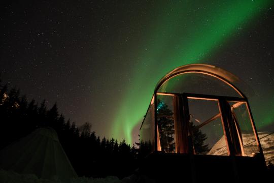 glass cabin with northern lights above