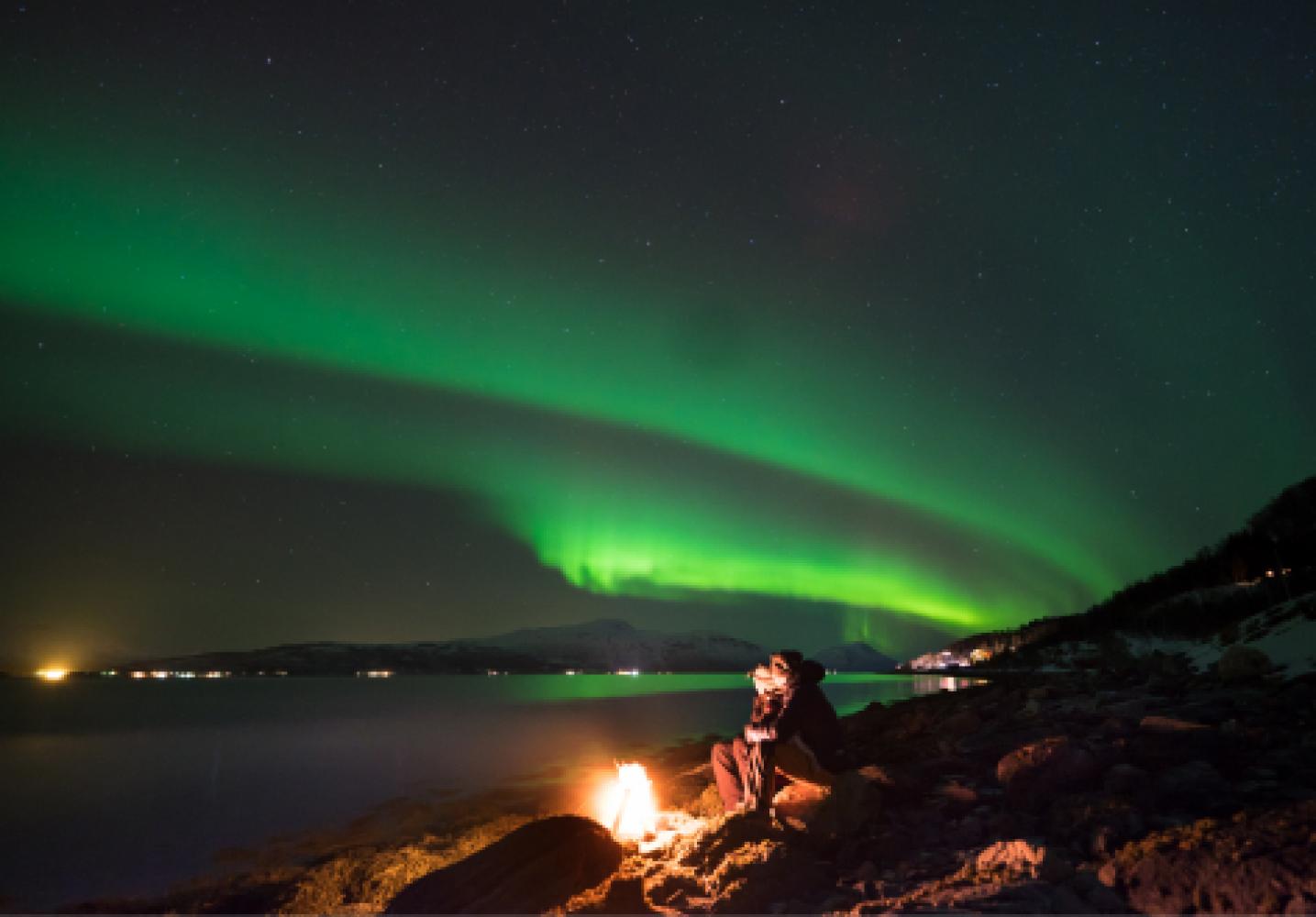 Enjoying the northern lights around a bonfire at the beach