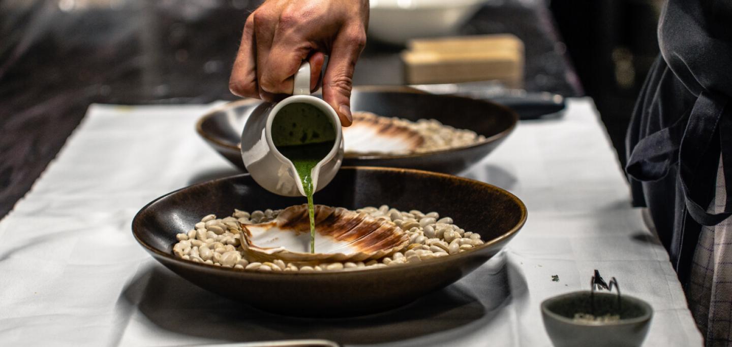 Chef pouring sauce for a scallop meal