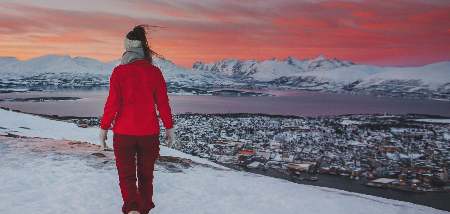 Person på fjelltur over Tromsø i solnedgang