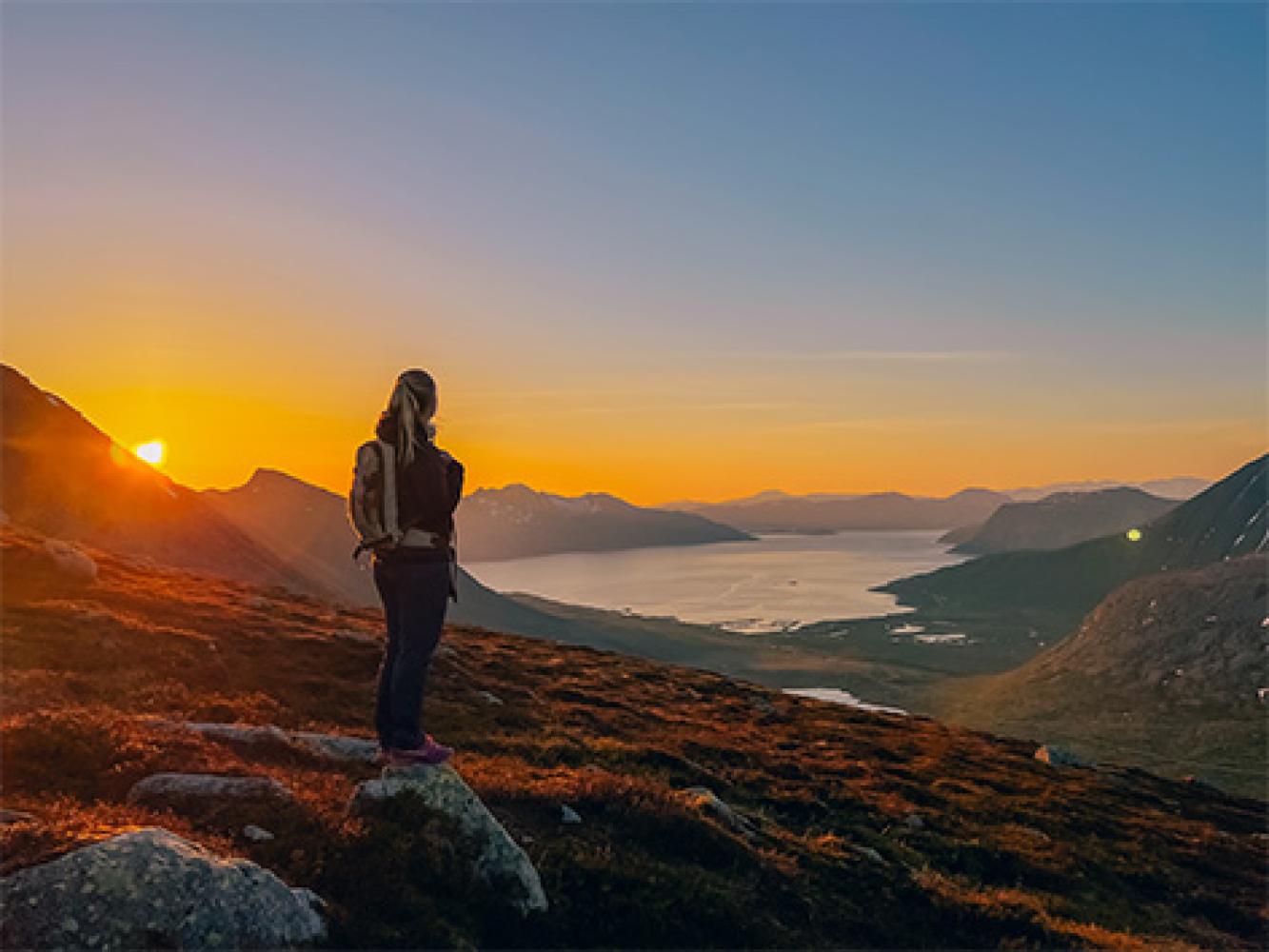 Woman enjoying the midnight sun and view from Kvaløya 