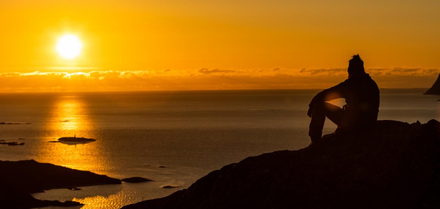 man watching the sunset over the sea during the midday sun
